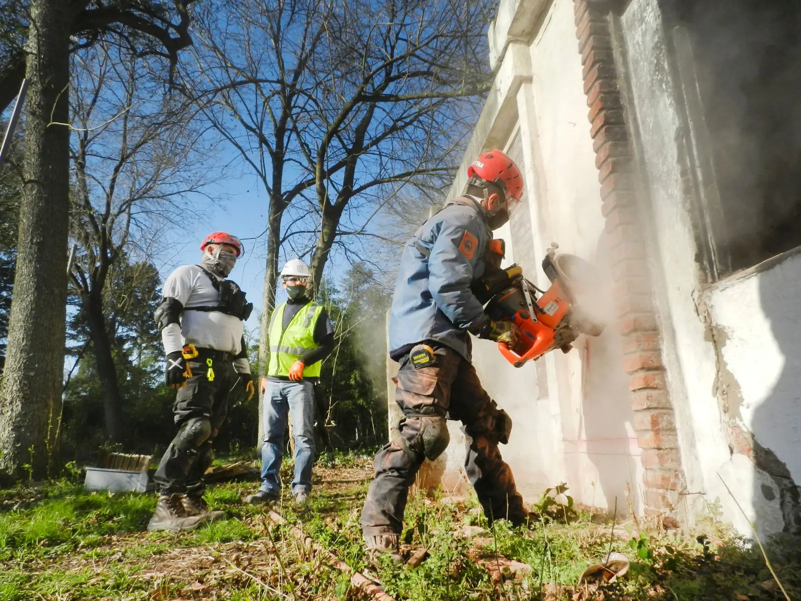 Team in Schutzausrüstung trennt mit Schneidgerät asbestzementhaltige Bauteile