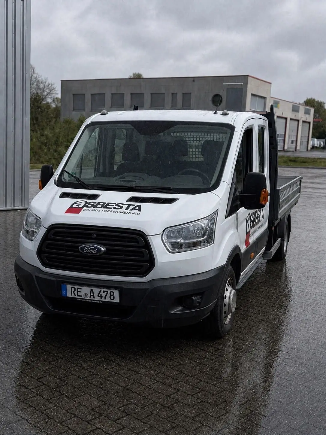 Firmen-Transporter von Asbesta mit Firmenlogo, abgestellt vor der Betriebshalle