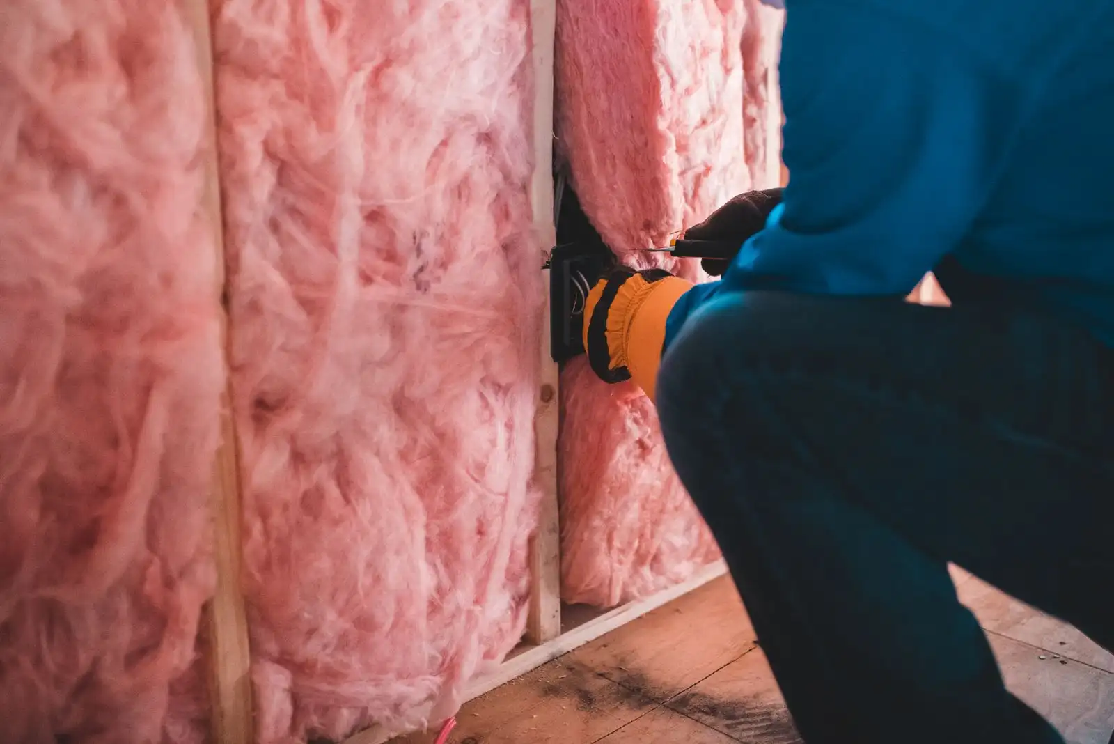 Fachkraft baut mit Handschuhen künstliche Mineralfaser-Dämmung aus